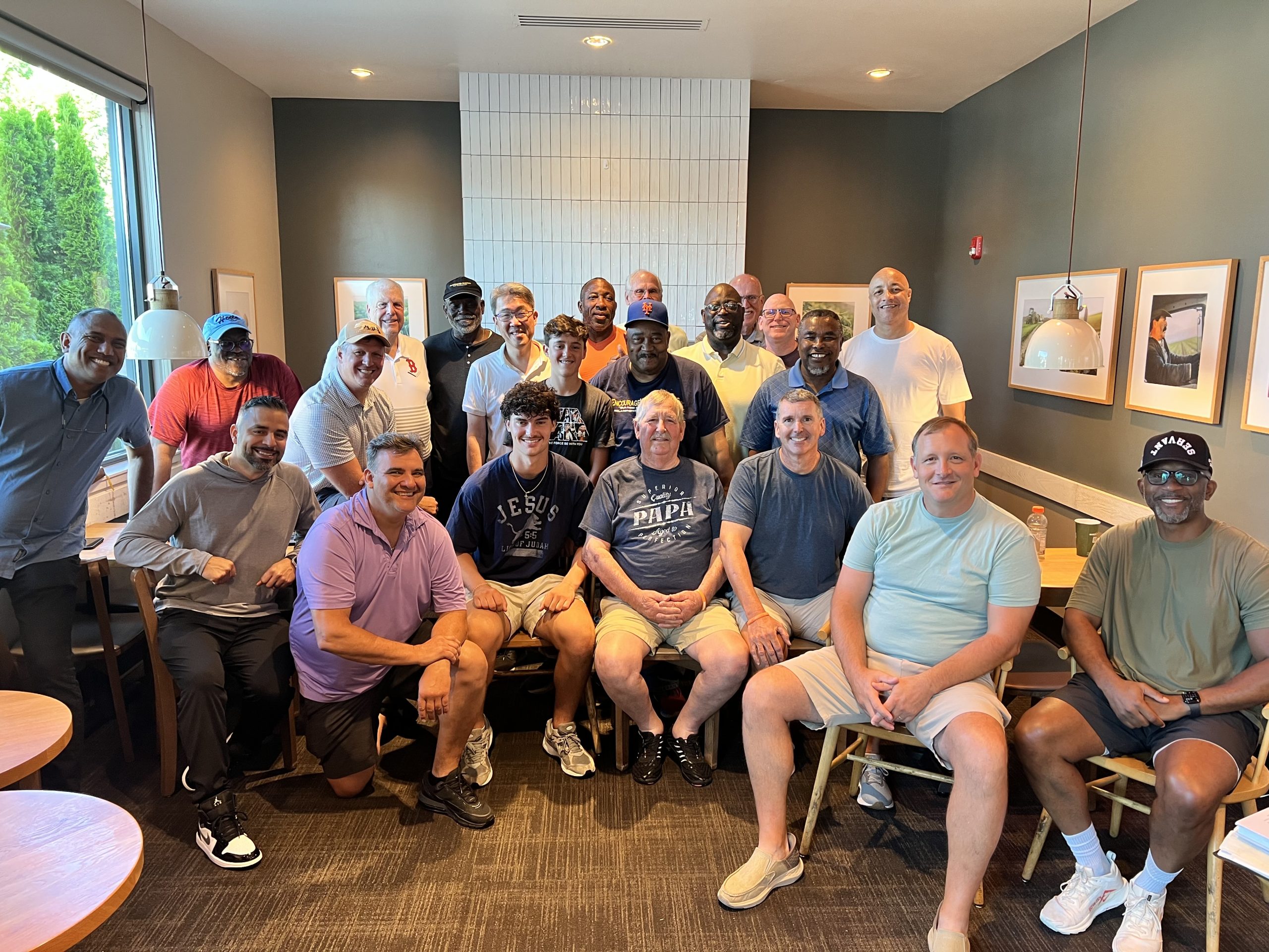A multicultural, multigenerational group of about two dozen men from Fellowship of the Fervent smiling together after a Saturday gathering